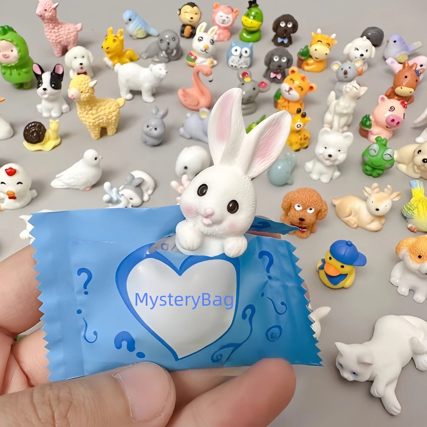 Blue animal mystery bag opened in front of assorted 3D resin zoo and pet figures