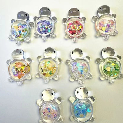 Ten clear mini turtle figures filled with colorful glitter sequins