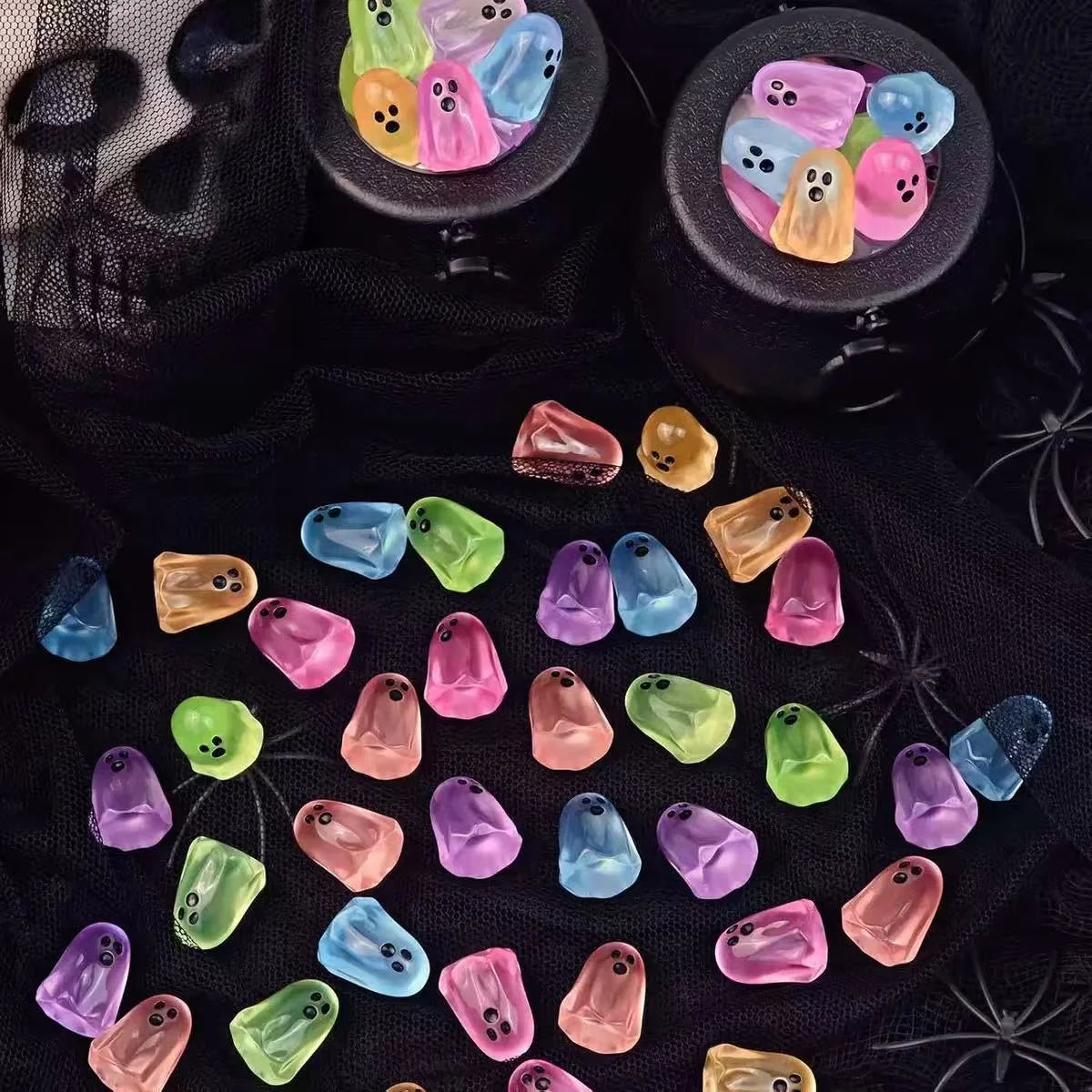 Pastel mini resin ghost figurines arranged on black Halloween fabric