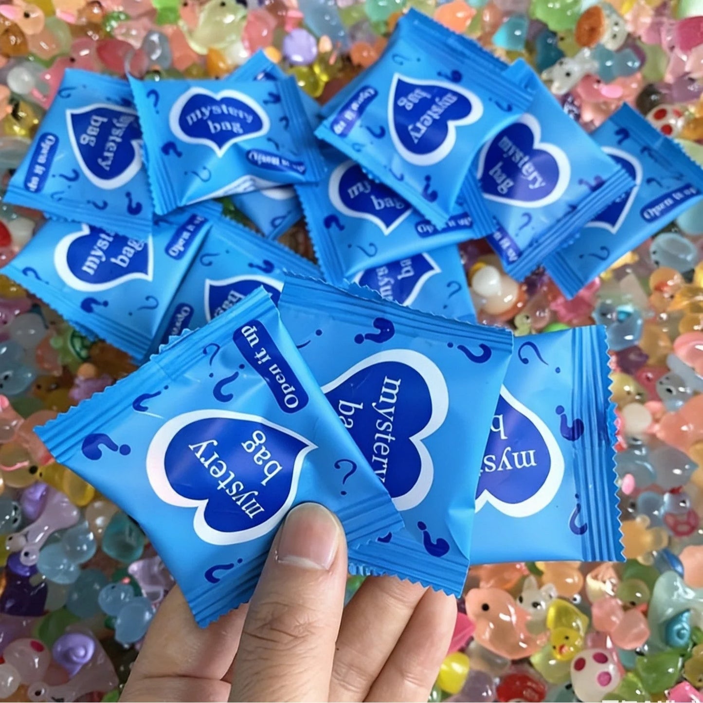 Multiple blue animal mystery bags displayed over colorful mini resin figures